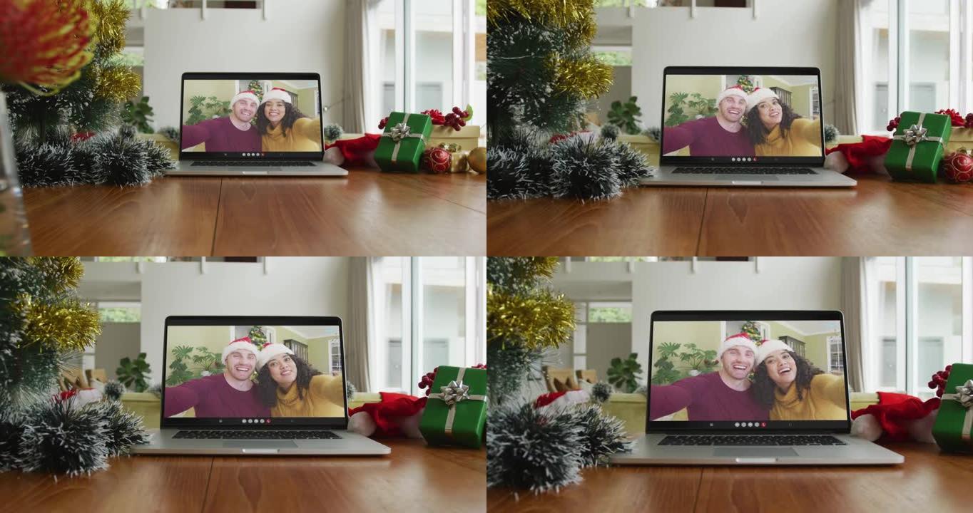 在圣诞节视频通话中戴着圣诞老人帽子的微笑夫妇在笔记本电脑上