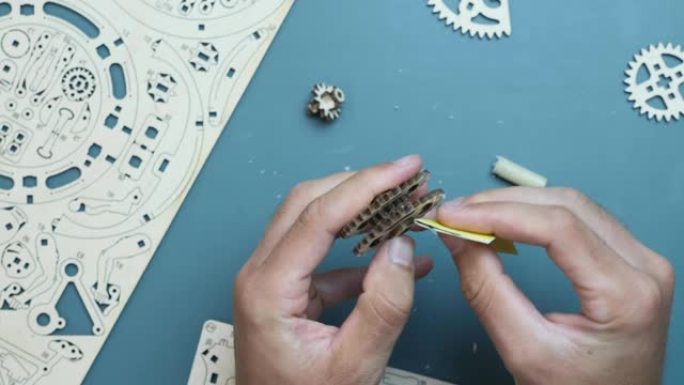 手用砂纸在家里的桌子上组装机械木制拼图玩具。休闲活动游戏