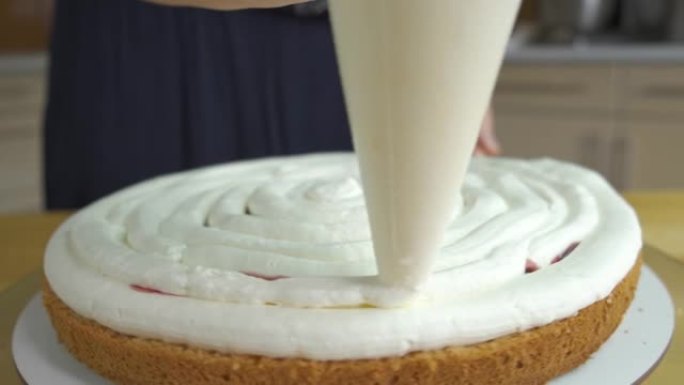 女人用白色奶油和饼干制作甜蛋糕的特写镜头。