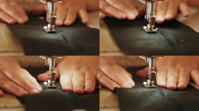 裁缝的手是用白色工业缝纫机缝制拉链 (拉链) 的裆黑色裤子特写。