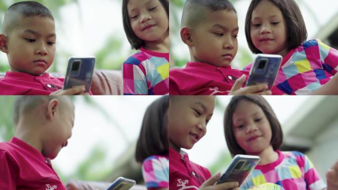 坐在花园里的智能手机的小男孩和女孩。