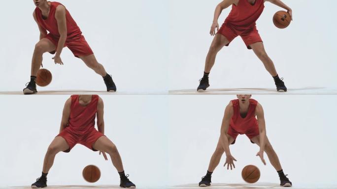 球技运球篮球运动员在工作室的白色背景。一个穿着红色运动服的高个子年轻运动员在地板上击球。特写。慢动作