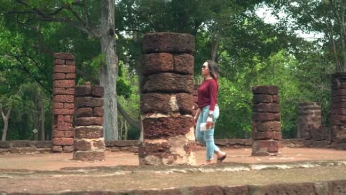 年轻的泰国女子步行去崇拜一个古老的佛教雕像与纸地图探索历史时刻在著名的古老甘榜Phet寺庙，背面的视