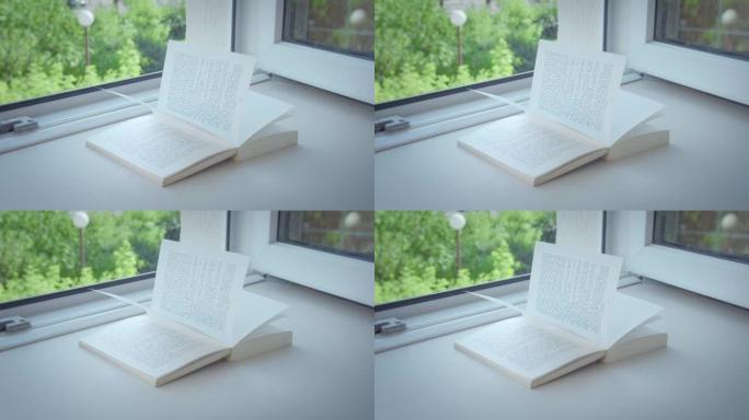 窗台上敞开的窗户放着一本打开的书，阳光明媚的日子