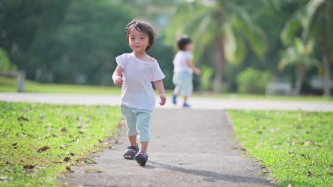 周末早上，兴奋的亚洲中国男婴在公园里奔向摄像机