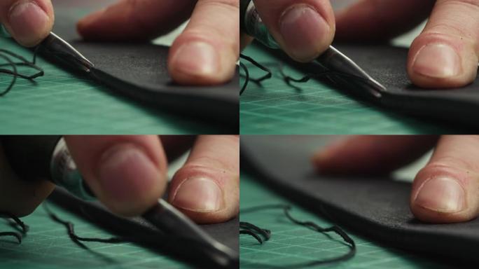 男人用锋利的刀在黑色皮革上切割细线特写。工匠在工作场所的桌子上雕刻皮肤材料，制作由真皮或人造革制成的