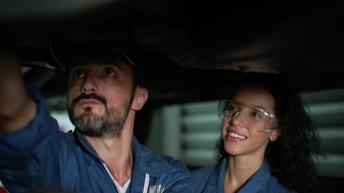 拉丁女机械师和男性一起在汽车下工作