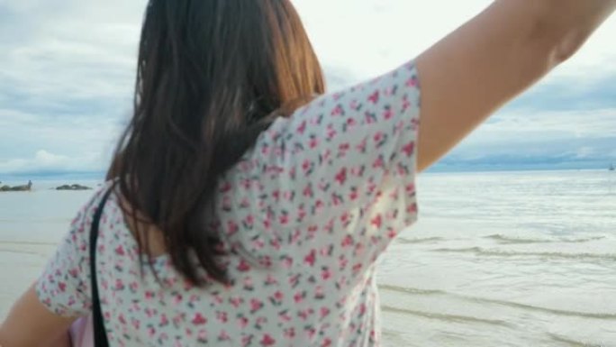 快乐的亚洲母亲和女儿在早晨的阳光下一起在海滩上举起心形的手，生活方式的概念。