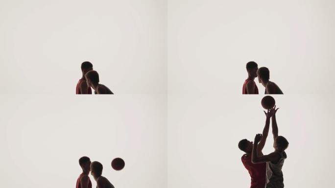 篮球比赛中比赛开始前的掷界外球。两名对方球员为控球而跳跃。剪影。慢动作