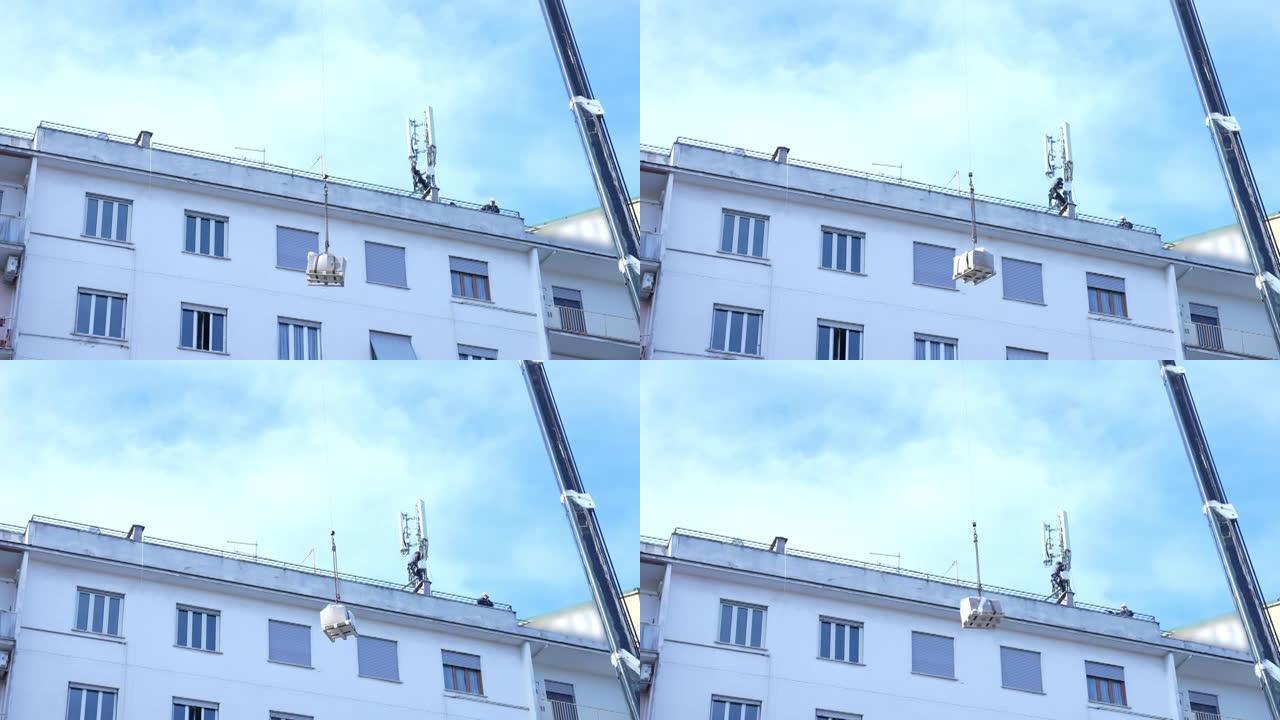 全球通信进步在世界，在意大利的建筑工地工作的电信工人安装5g塔。建筑屋顶顶部的工程起重机起重蜂窝站设