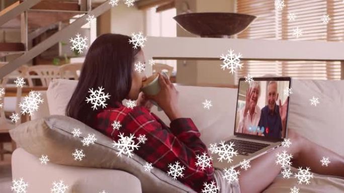 圣诞节时，与家人在笔记本电脑视频通话中下雪的混合种族妇女的动画