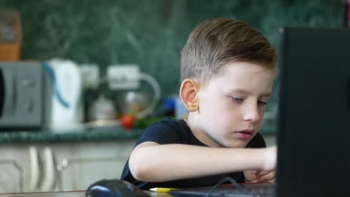 7-9岁的高加索男孩专心地坐在笔记本电脑屏幕上，在家中键盘上打字。左侧的复制空间。互联网上的孩子，在
