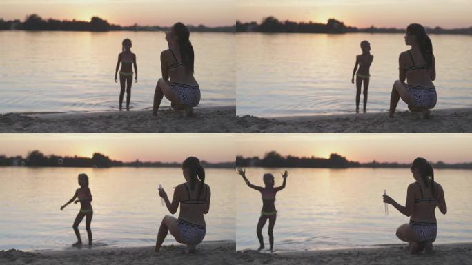 有趣的女孩抓住湖边的泡沫，她的姐姐放开了