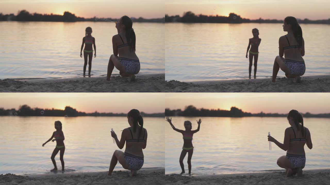有趣的女孩抓住湖边的泡沫，她的姐姐放开了
