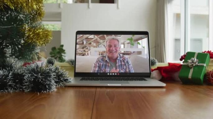 微笑的白人男子挥舞着笔记本电脑上的圣诞节视频通话