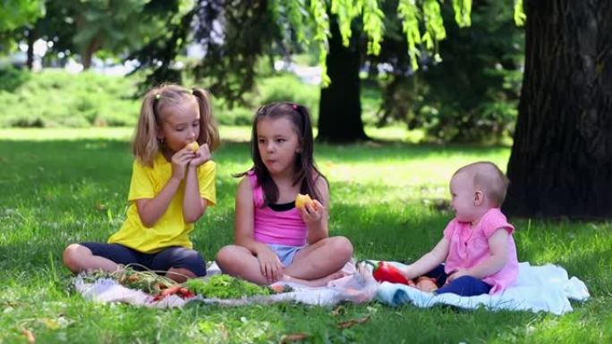 三个小女孩正在绿色草坪上吃梨