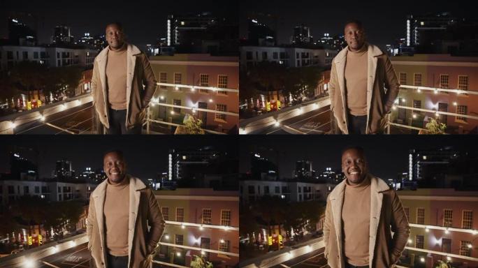 黑人男性站在城市的屋顶上，在夜晚自信地微笑。高质量4k镜头