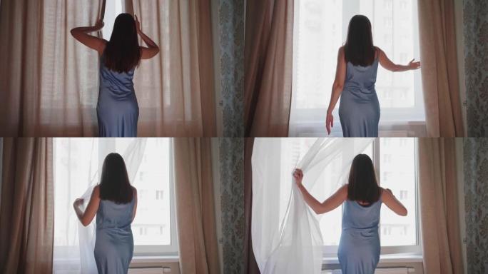 年轻女子走近窗户，用手推开窗帘和白色薄纱，打开窗户，享受清新的微风。她有一头黑发，穿着蓝色衬衫。早晨