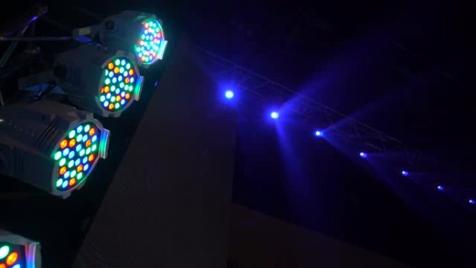 五颜六色的投影仪挂在音乐农场上。聚光灯在音乐厅旋转闪烁。自动化灯光舞台技术。