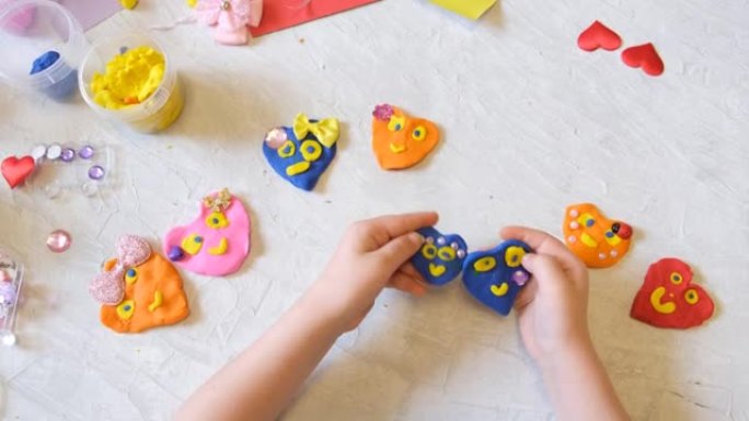 小女孩的手用五颜六色的粘土面团、橡皮泥、家庭教育游戏制作花和太阳等。