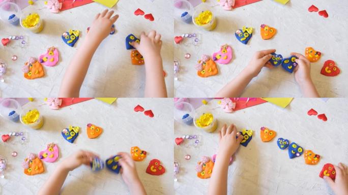 小女孩的手用五颜六色的粘土面团、橡皮泥、家庭教育游戏制作花和太阳等。