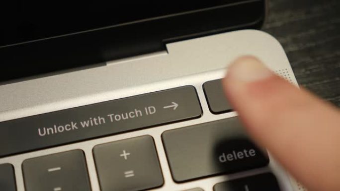 人类手指使用指纹生物识别扫描仪在笔记本电脑上进行安全访问。高科技数据安全。用户用指纹扫描仪解锁笔记本