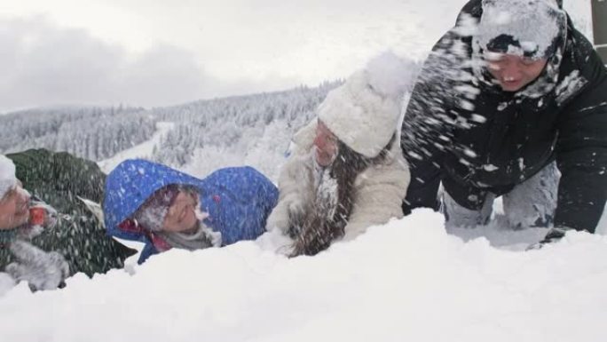 一群朋友兴高采烈地互相撒雪。美好的冬日。在白雪皑皑的森林背景下