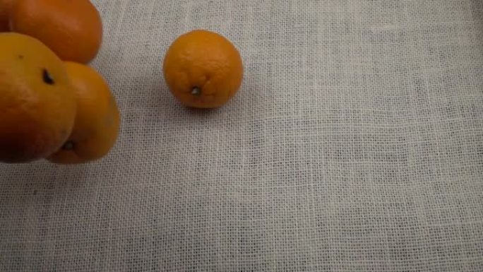 橘子落在白色的粗麻布上，慢动作