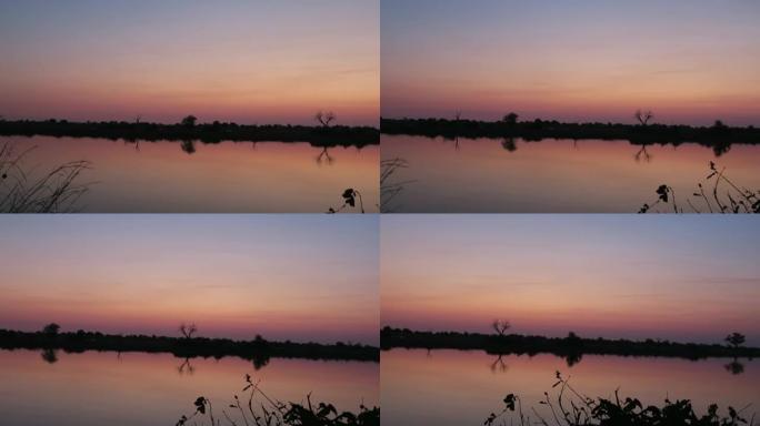 日落之后，非洲河的安静beaty天空中带有紫色的色调反射如果河的两岸都可以看到枯死的树，相机沿着河从