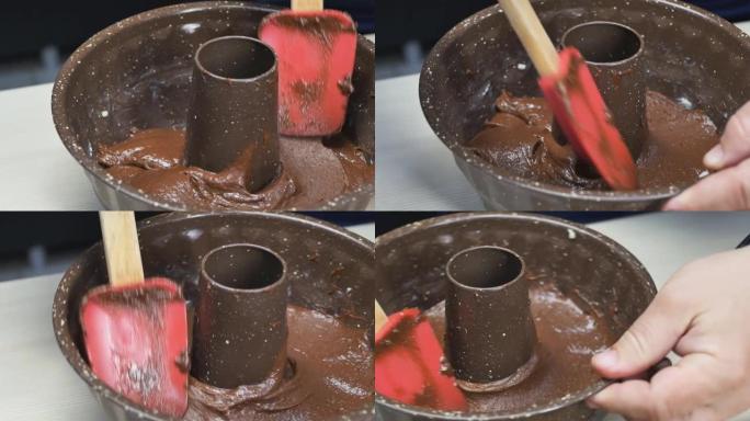 糕点厨师用硅胶烹饪刮铲将圆形蛋糕或松饼锅内的棕色面团抚平。特写。