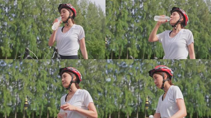 亚洲女人休息一下，骑自行车后从瓶子里喝水。活跃的年轻运动员运动女孩通过骑自行车锻炼来锻炼健康保健和晚