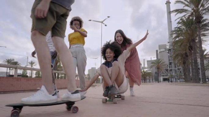 一群年轻人在城市里玩滑板。千禧一代的朋友们庆祝相聚。多种族的人。