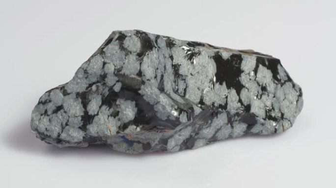 矿物雪黑曜石。石头是白色背景上的火山起源。