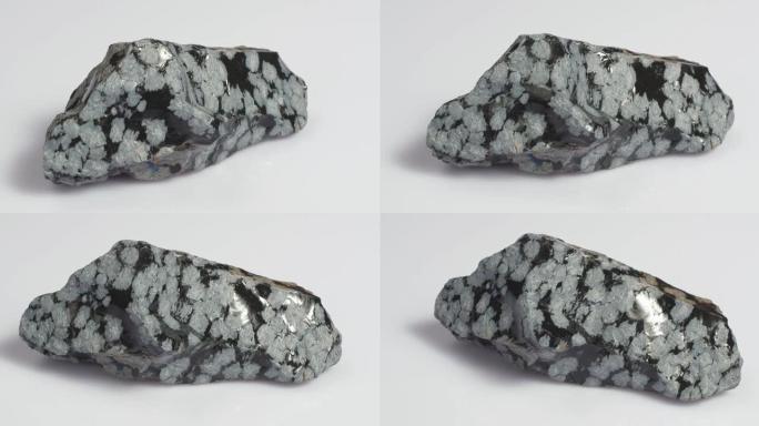 矿物雪黑曜石。石头是白色背景上的火山起源。