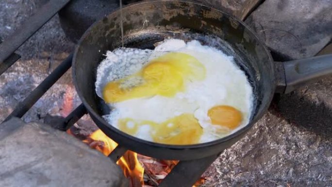 男性，游客在户外的煎锅里用篝火炸鸡蛋。特写