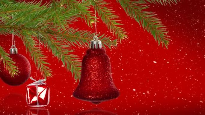 红色背景下悬挂在树枝上的圣诞装饰品上的雪