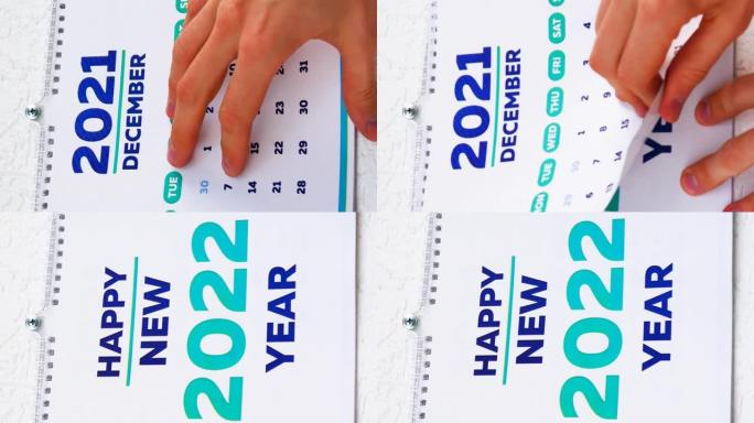 男性手的特写镜头撕下2021年挂历的12月页，然后是新的2022日历的标题页。垂直视频