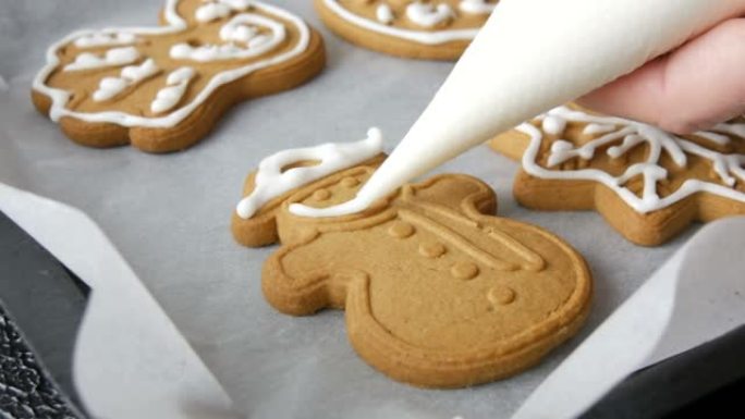 圣诞节日姜饼饼干。女性手工装饰糕点袋，家庭厨房配有甜白色糖衣雪人形饼干