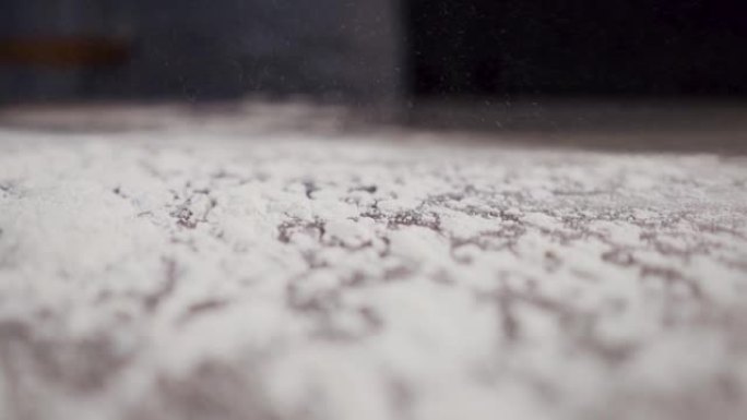 新鲜的白面粉散落在厨师的桌子上。慢动作