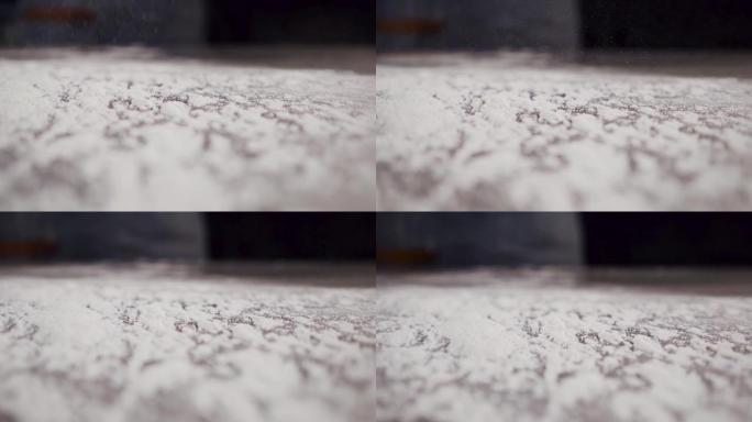 新鲜的白面粉散落在厨师的桌子上。慢动作