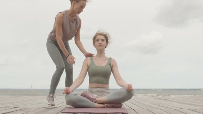 女人在码头上与教练一起练习瑜伽