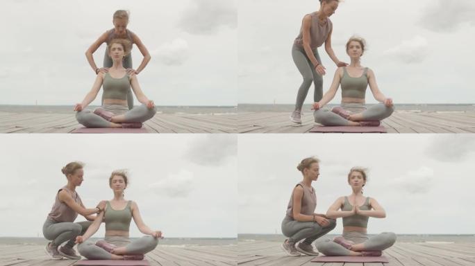 女人在码头上与教练一起练习瑜伽