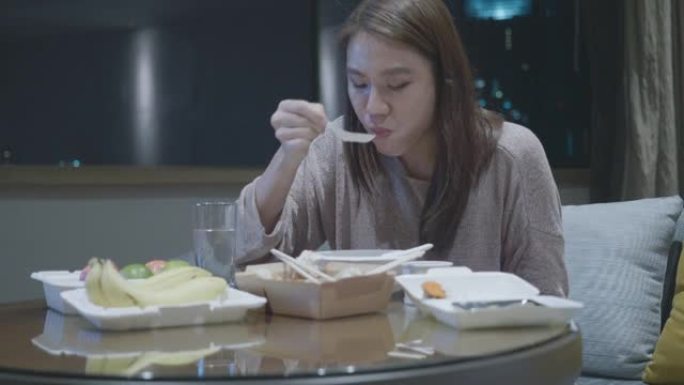 东南亚妇女一边看电影一边吃外卖食物