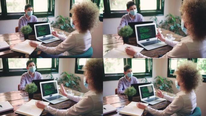 负责任的现代女企业家，戴着防护口罩，在自助餐厅的笔记本电脑上工作