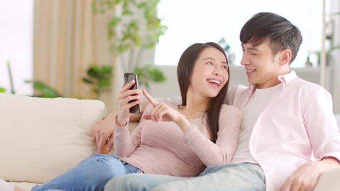 幸福的年轻夫妇在家里的客厅看手机