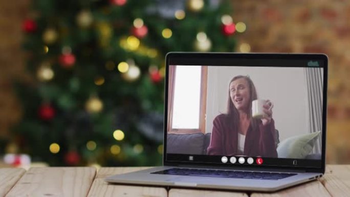快乐的高加索高级妇女在笔记本电脑上进行视频通话，带有圣诞节装饰和树木