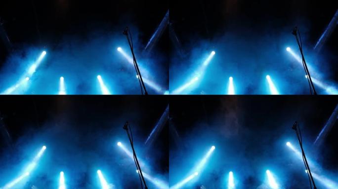 蓝色的舞台灯光升起。前视图。现场有六条光线和麦克风。彩色明亮的舞台灯