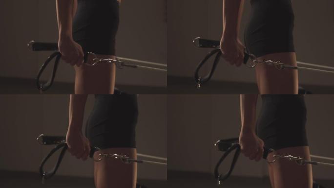 年轻健康的运动女性在普拉提重整机器上锻炼背部和腿部，用皮带在张力弹簧上移动平台