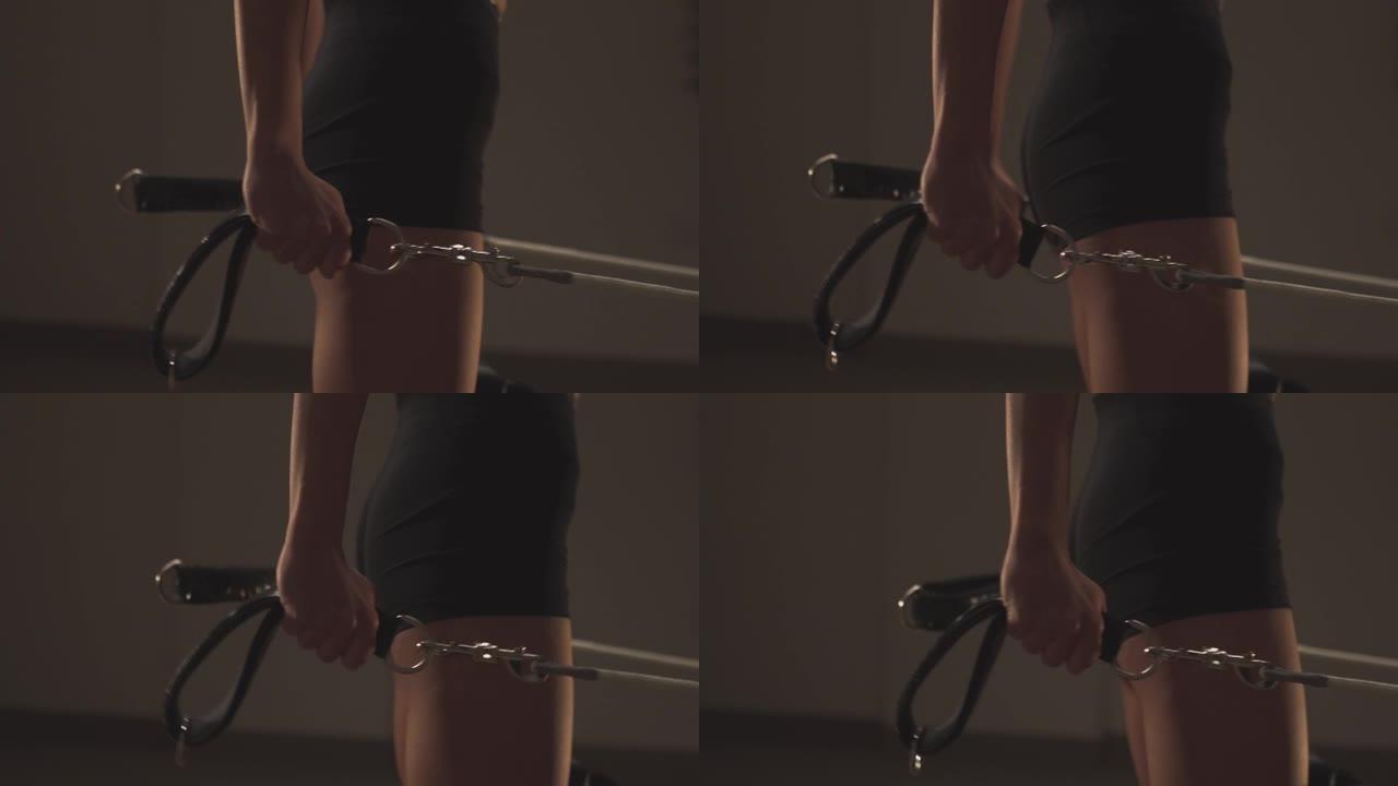年轻健康的运动女性在普拉提重整机器上锻炼背部和腿部，用皮带在张力弹簧上移动平台