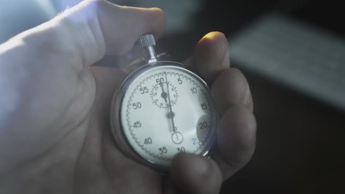 一个男人手中的秒表。一名男子按下老式运动金属第二手表的按钮。倒计时，活动前的计时器